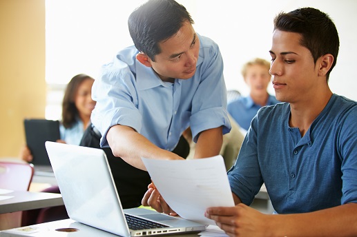 Students With Teacher In Class Using Laptops