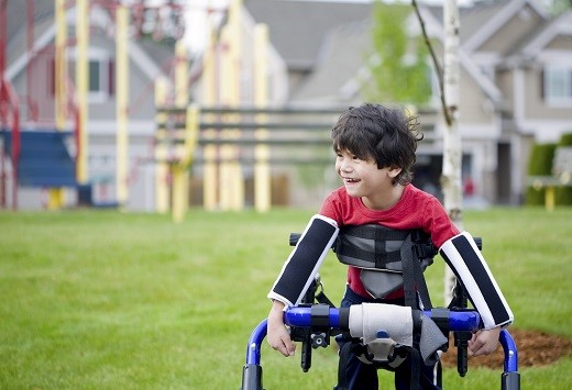 Assistive Technology Boy in walker in front of playground