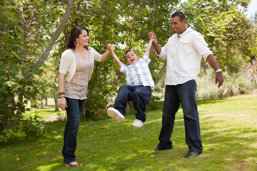 Hispanic Man, Woman and Child having fun in the park.