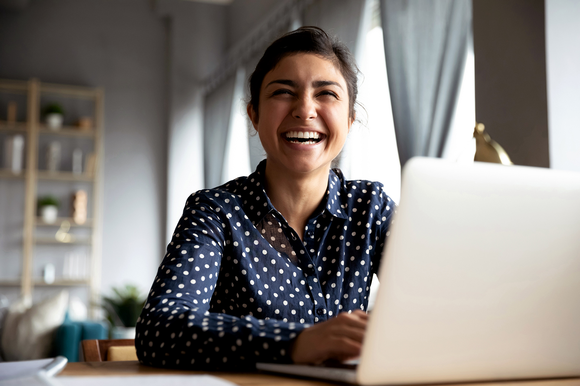 Cheerful indian girl laughing sit with laptop at table Parent with student computer