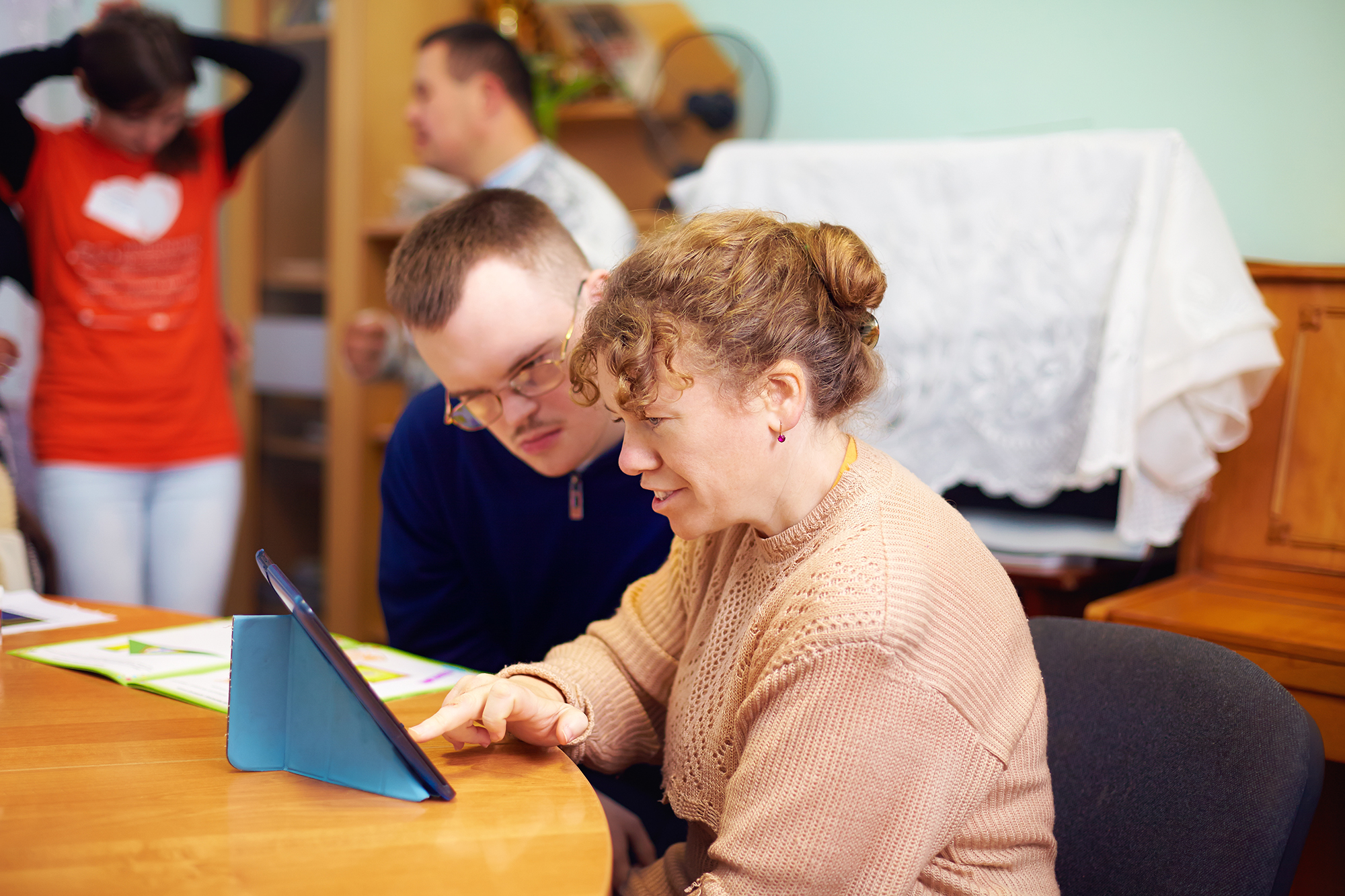 Adult student works with teacher on a tablet. 