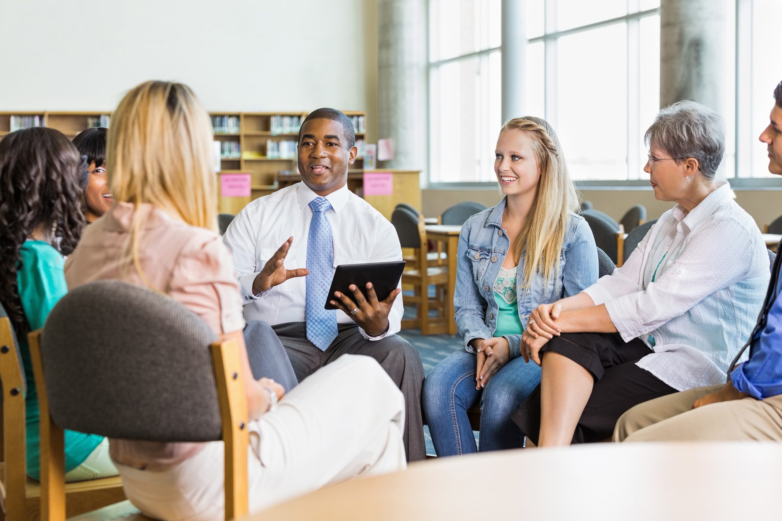 Man leading discussion group of adults and teens