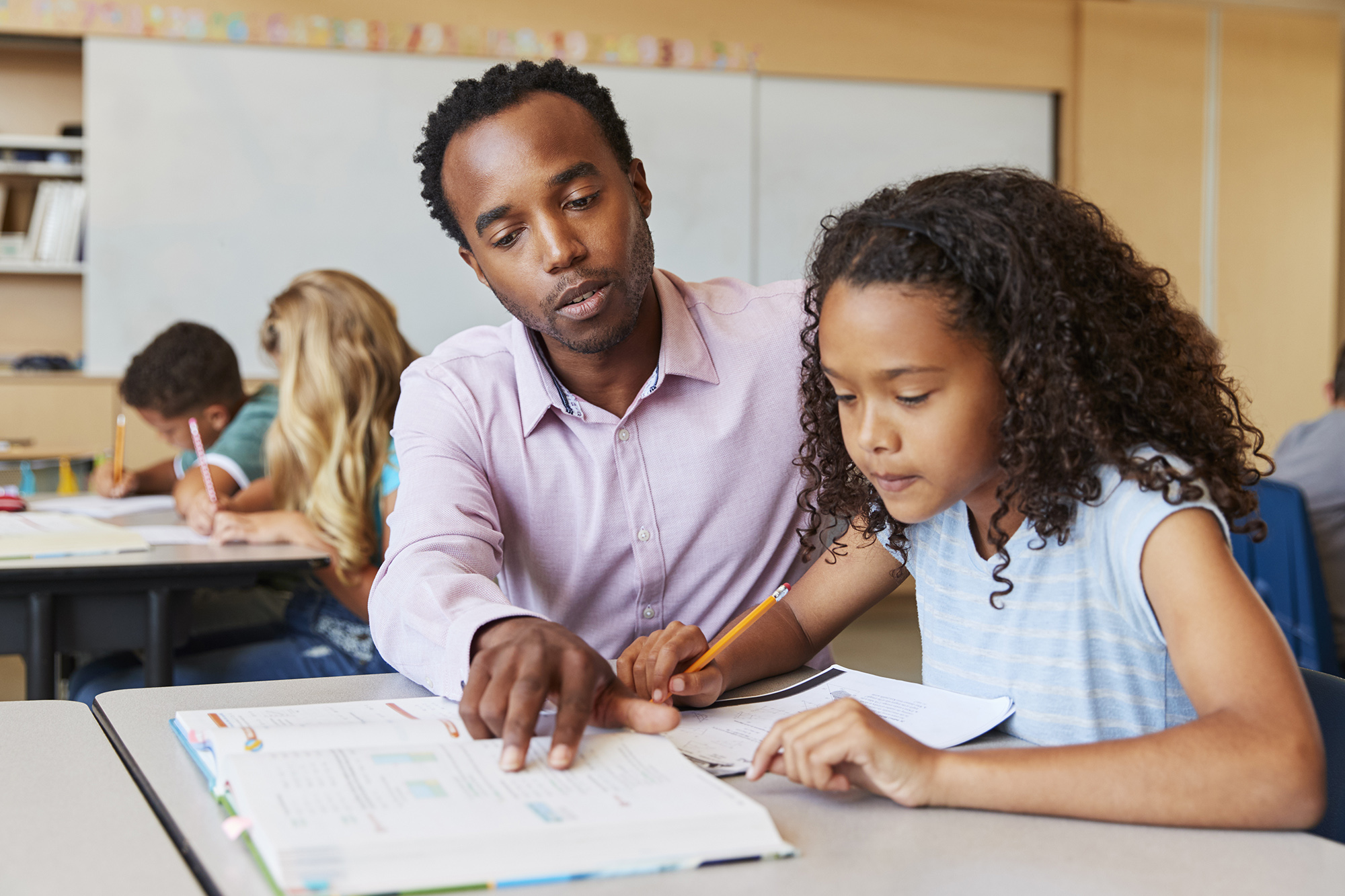 Teacher working with elementary school girl at her desk