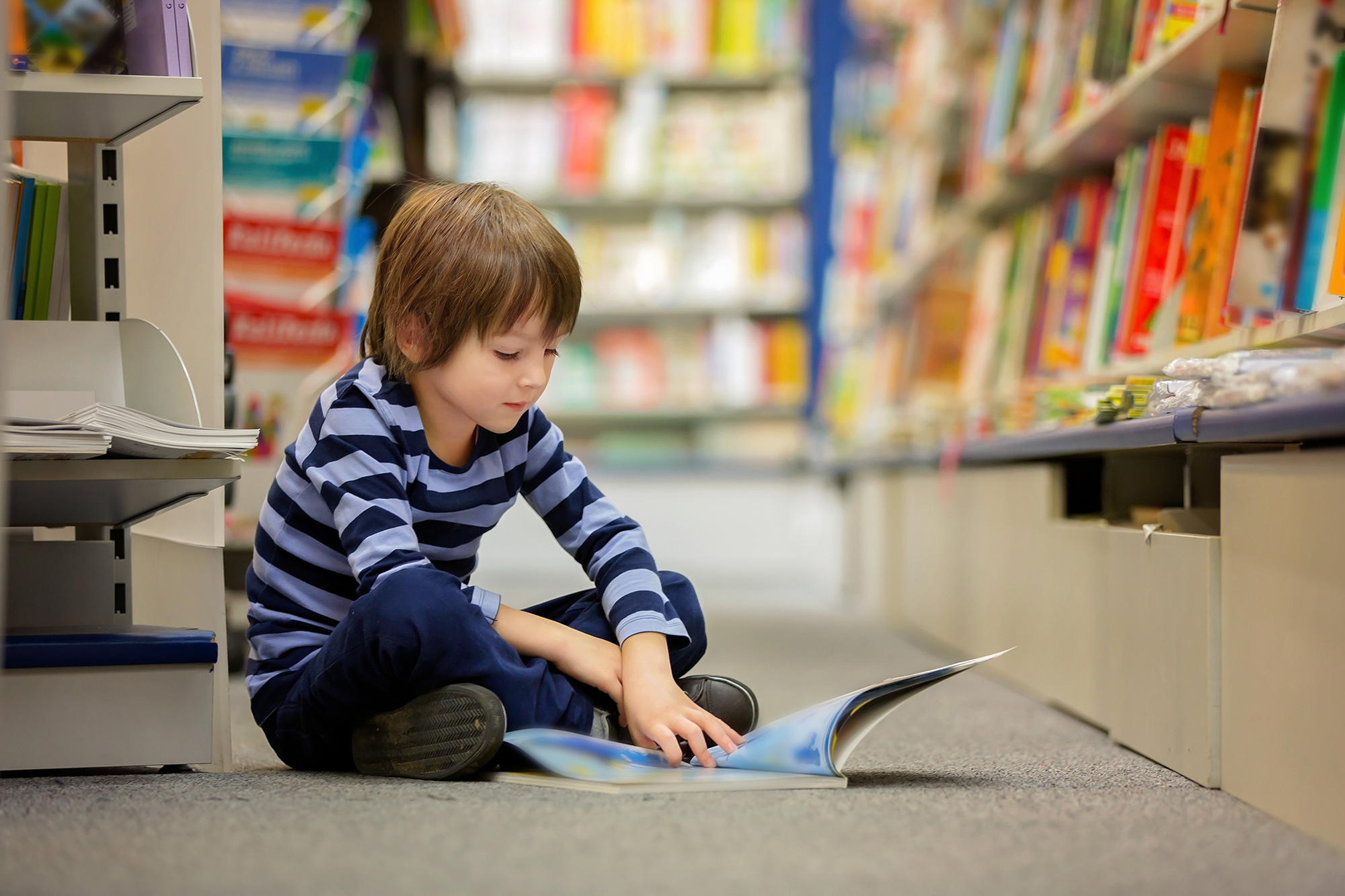 Adorable little child, boy, sitting in a book store, reading books Adorable little child, boy, sitting in a book store, reading books