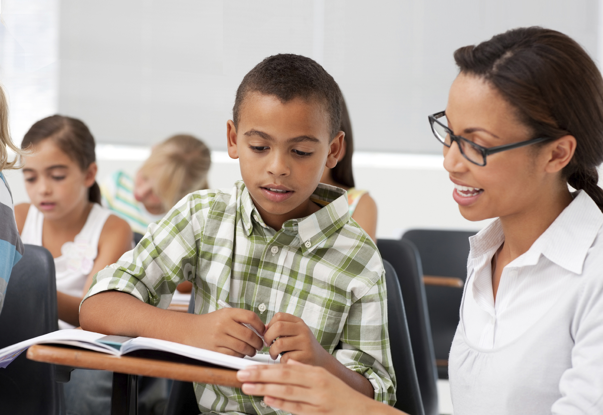 TeacherStudentsAge8-9 African American school boy being assisted by teacher with school work