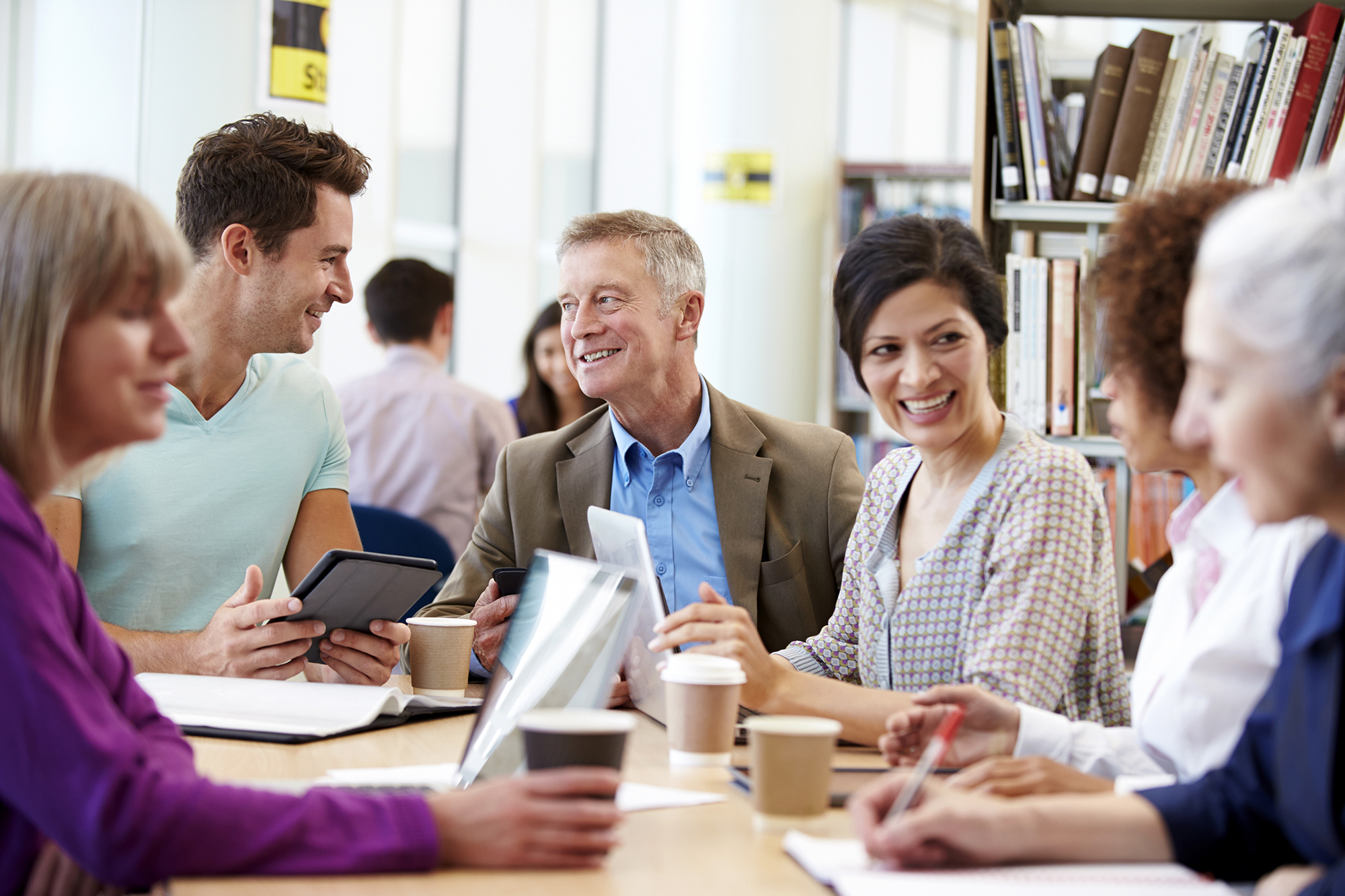 Group Of Mature Students Collaborating On Project In Library