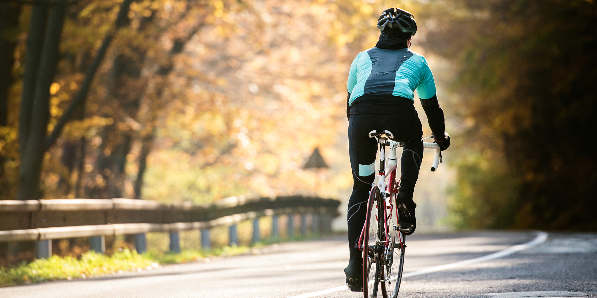 Young sportsman riding bicycle outside in sunny autumn nature