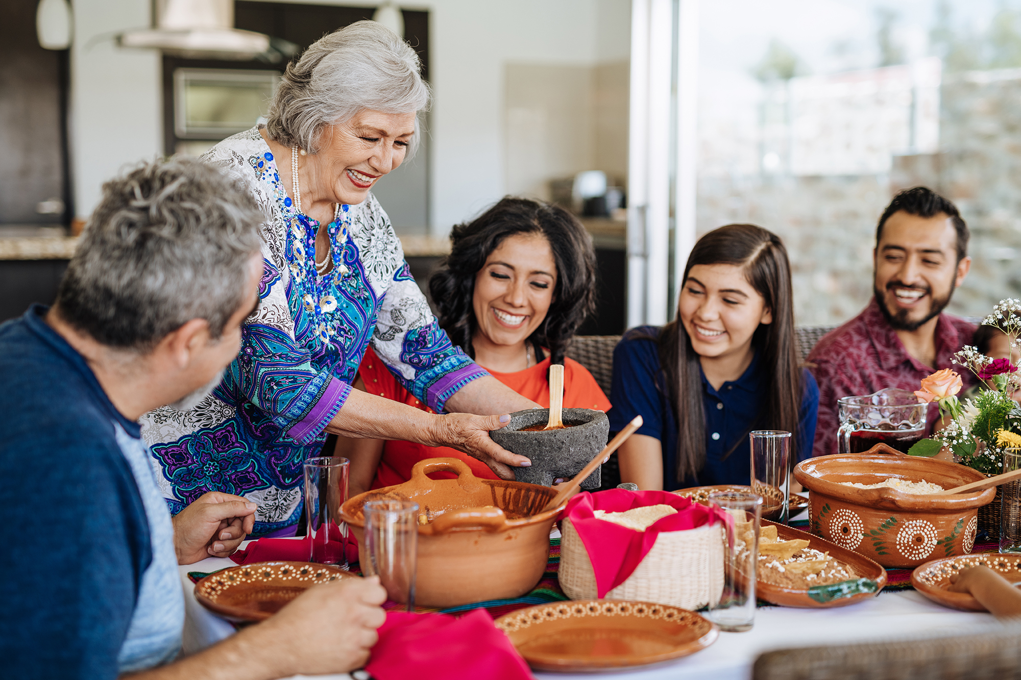 Cheerful senior Latin woman preparing lunch for her family