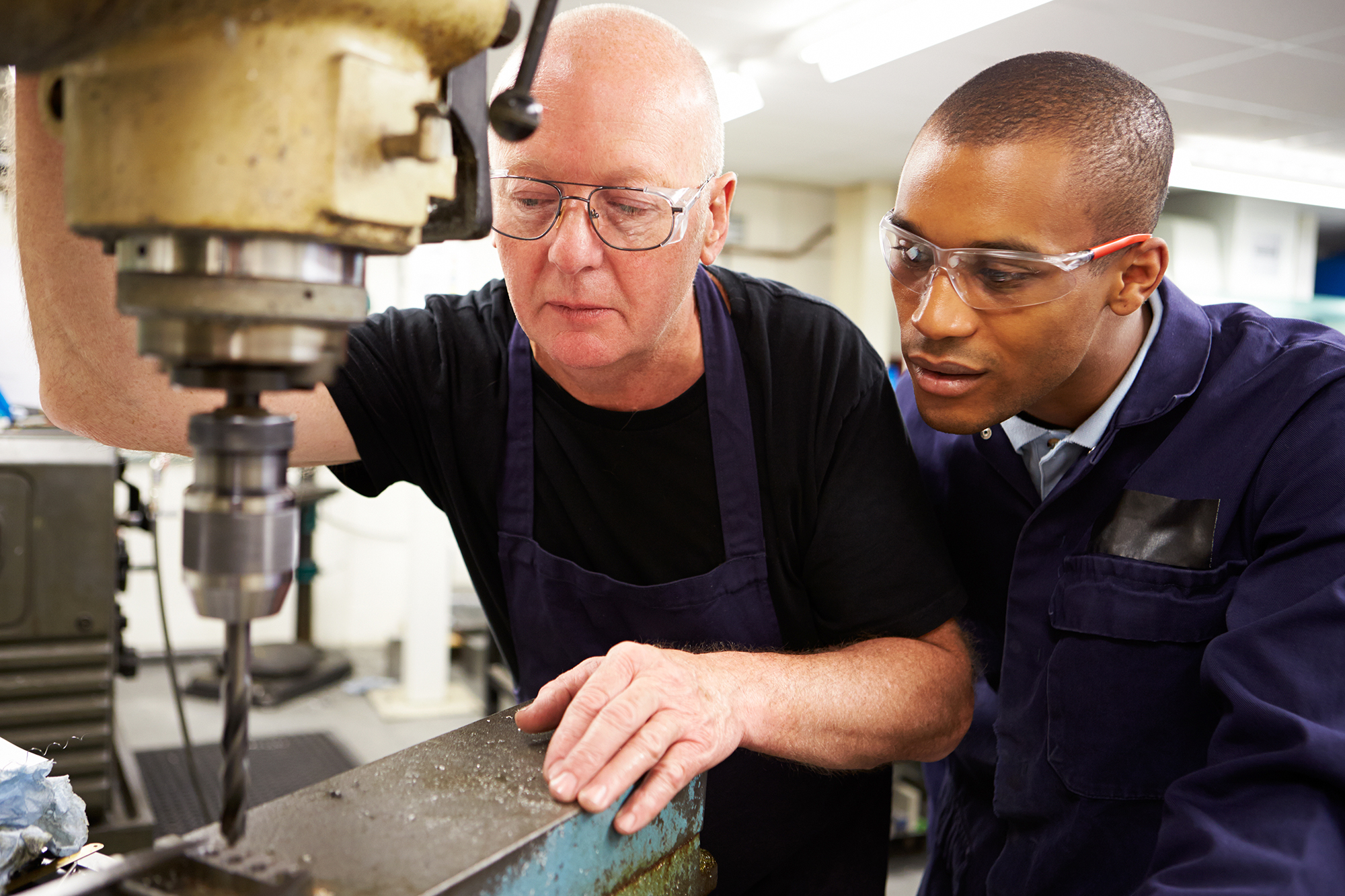 man showing a young person how to use a large drill