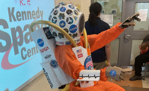 image of a space suit in front of a projector screen in a classroom