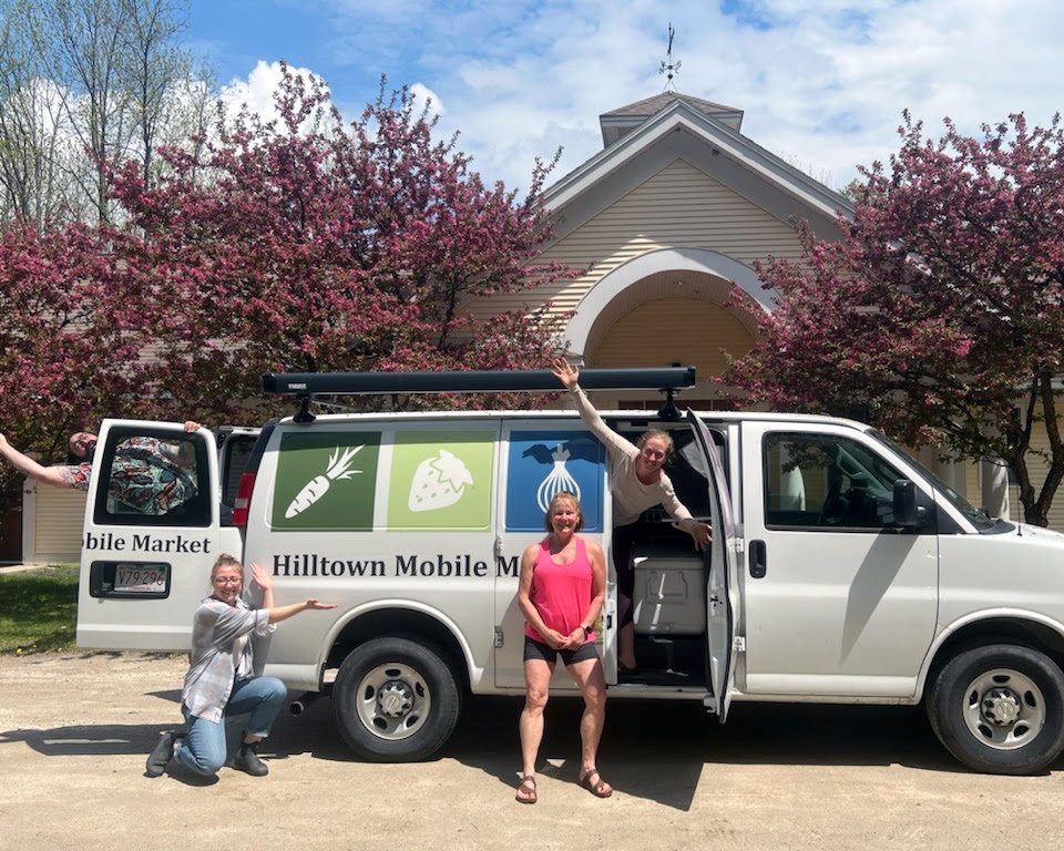 image of a van that says Hilltown Mobile Market on it, with three people standing in front presenting it