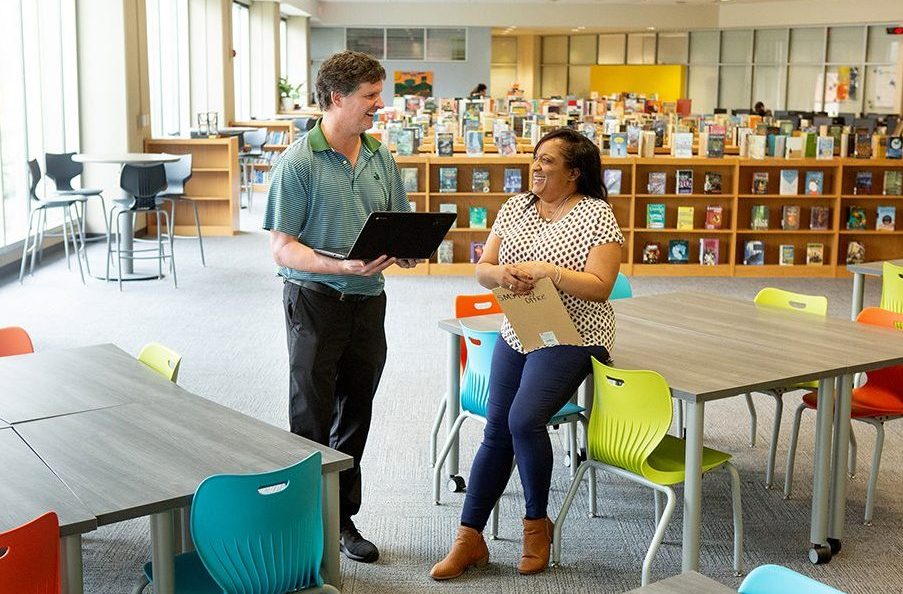 Two middle school teachers take a break in their school’s library.
