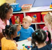 Preschool teacher with a group of preschool children at a table